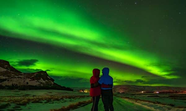 2 personnes sous les aurores boréales, également appelées lumières du nord, en Islande