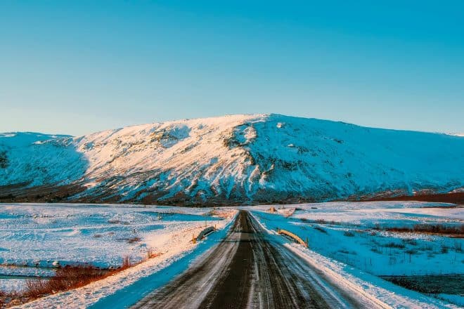 Route islandaise typique couverte de neige avec de petits bâtons jaunes sur le côté