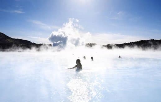 Women in the silky blue waters of the blue lagoon in Iceland with smoke in the background