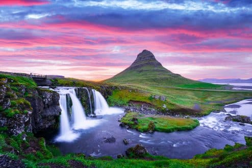 Mt. Kirkjufell on Iceland's Snaefellsnes Peninsula with a waterfall in the foreground and a pink cloudy sky