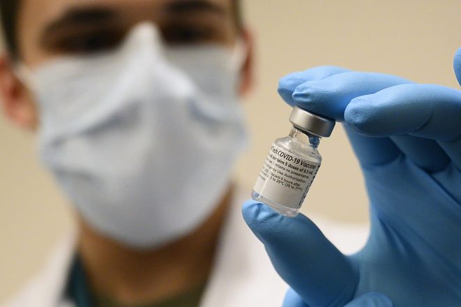 Army Spc. Angel Laureano holds a vial of the COVID-19 vaccine, 