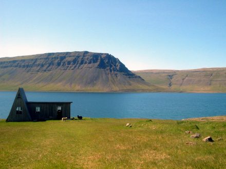 Maison abandonnée par un fjord et une montagne dans les Westfjords de l'Islande.