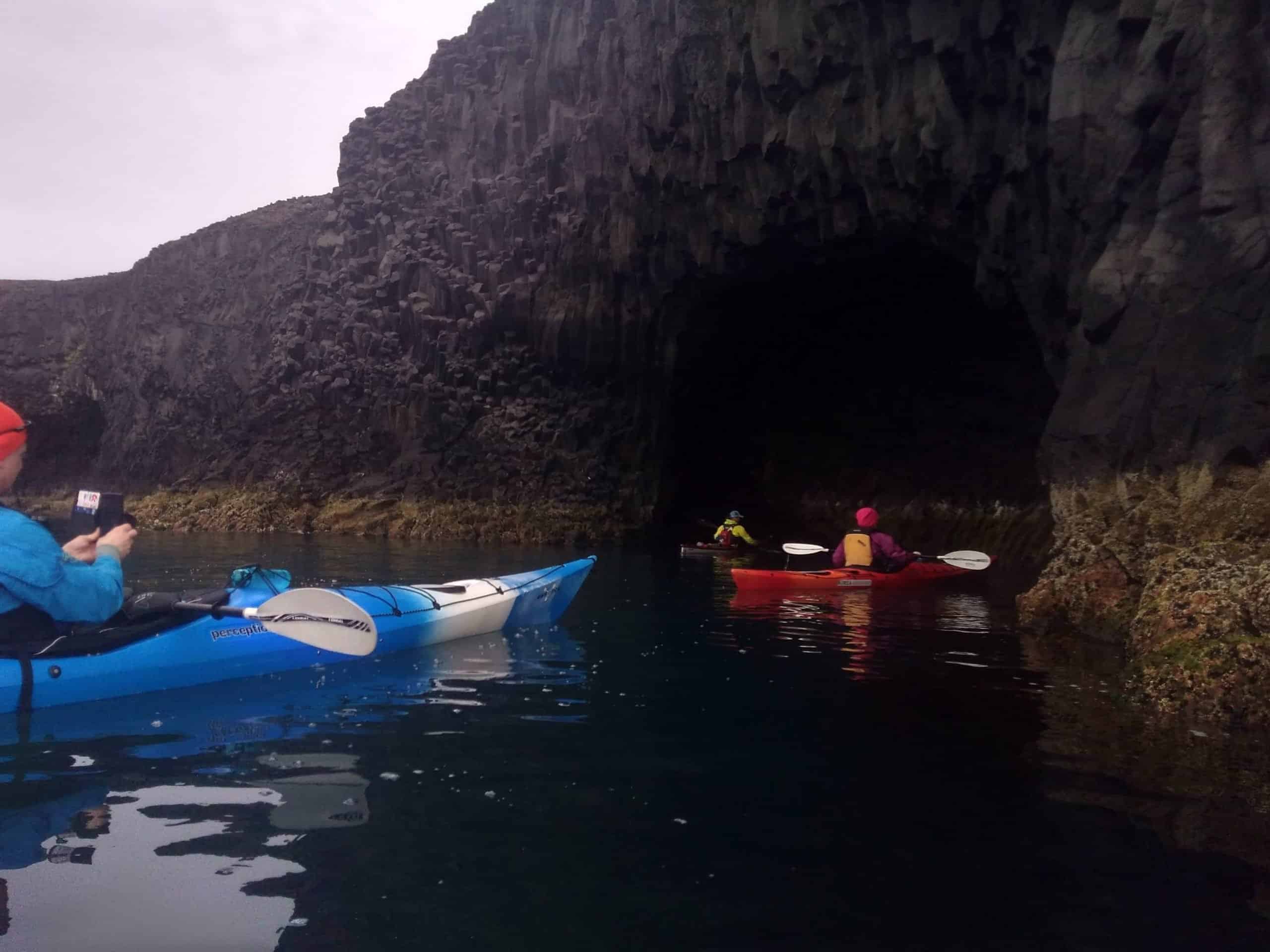 Kayakers sailing into a cave in North Iceland.