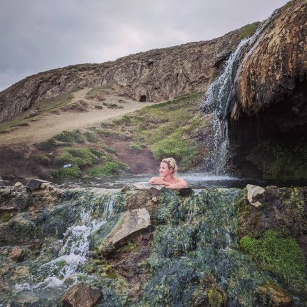 A woman bathing in a hot spring waterfall in East Iceland