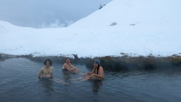 People bathing in a hot spring river in Iceland in the winter
