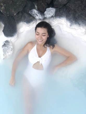 A woman in white bathing suite lying in the Blue Lagoon