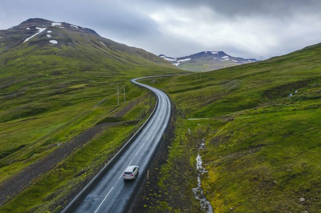 Voiture de location solitaire sur une route isolée avec de beaux paysages d'Islande.