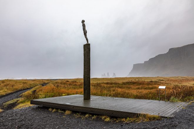 Statue of a man in Vik, Iceland with mountains in the background