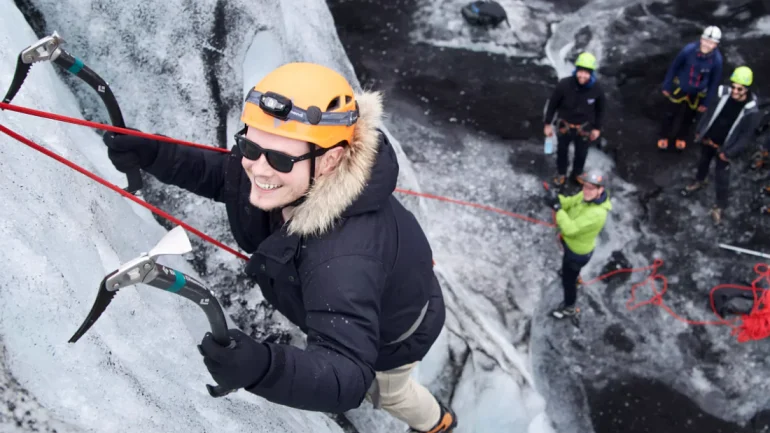 Un homme souriant lors d'une escalade sur glace en Islande